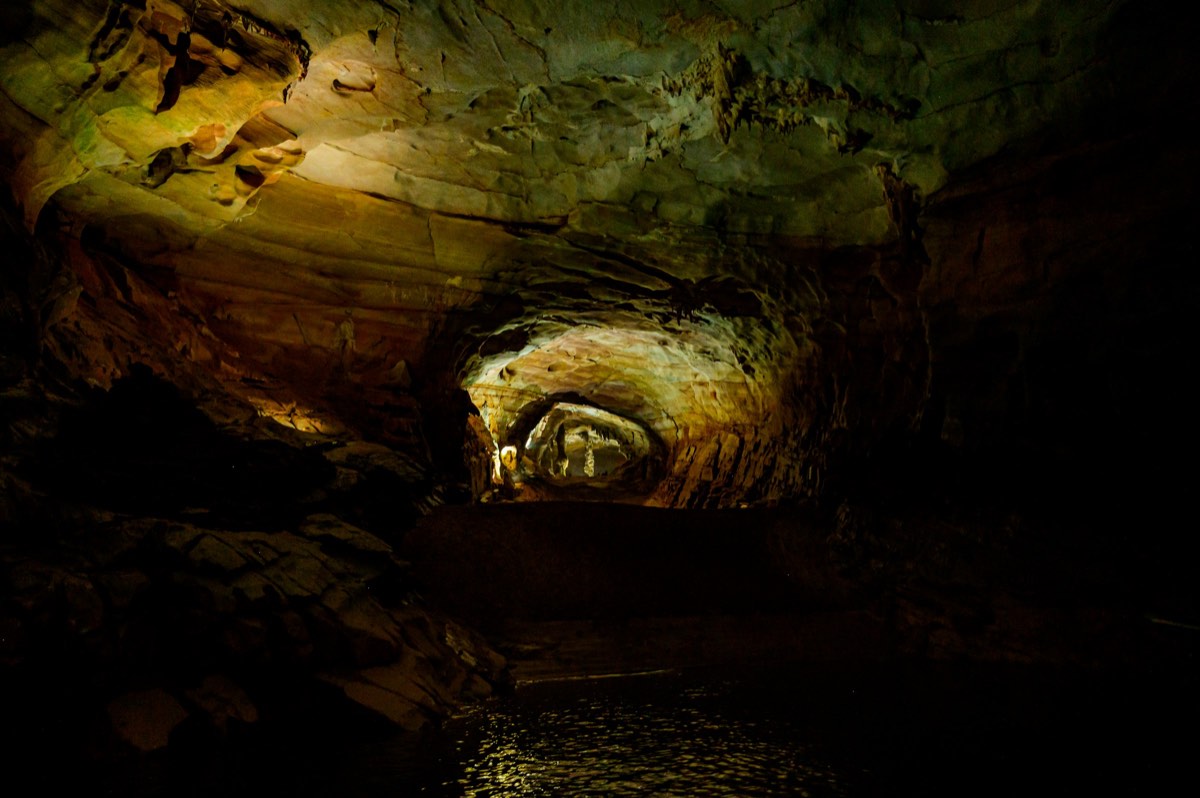 The underground river inside Phong Nha Cave, golden light on dark limestone