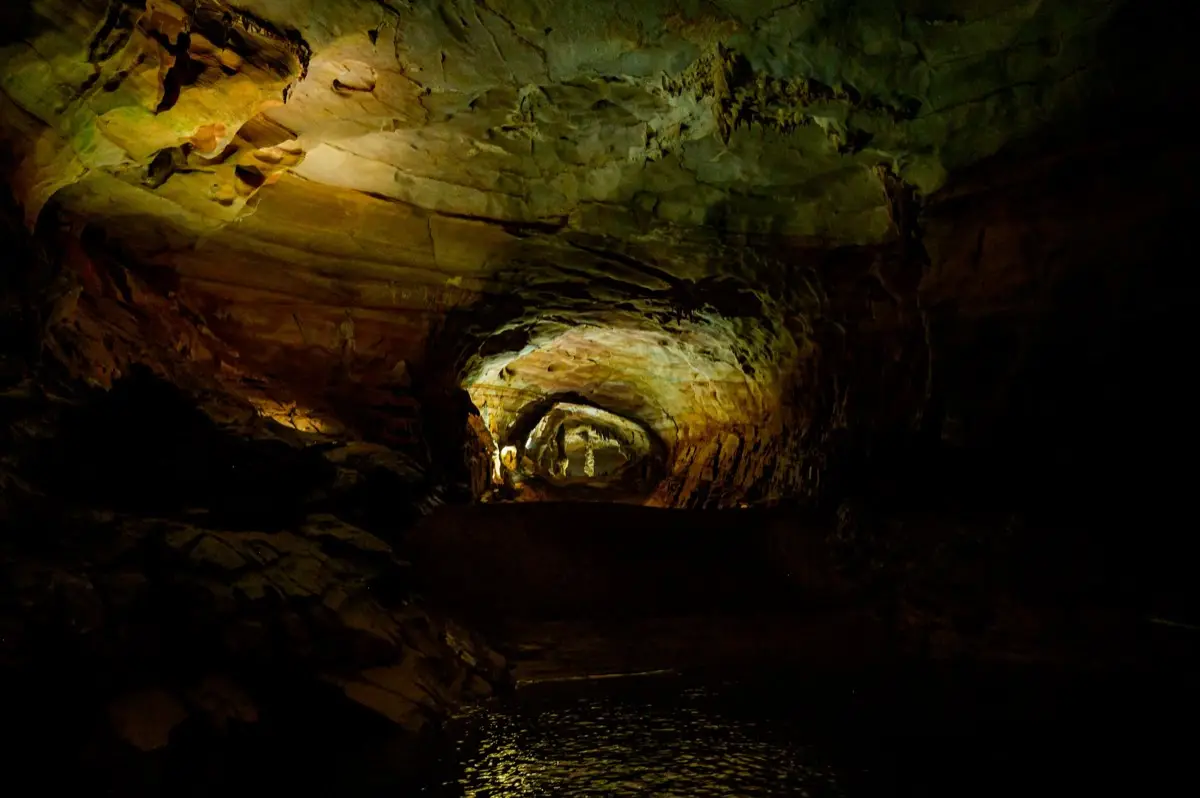 The underground river inside Phong Nha Cave, golden light on dark limestone