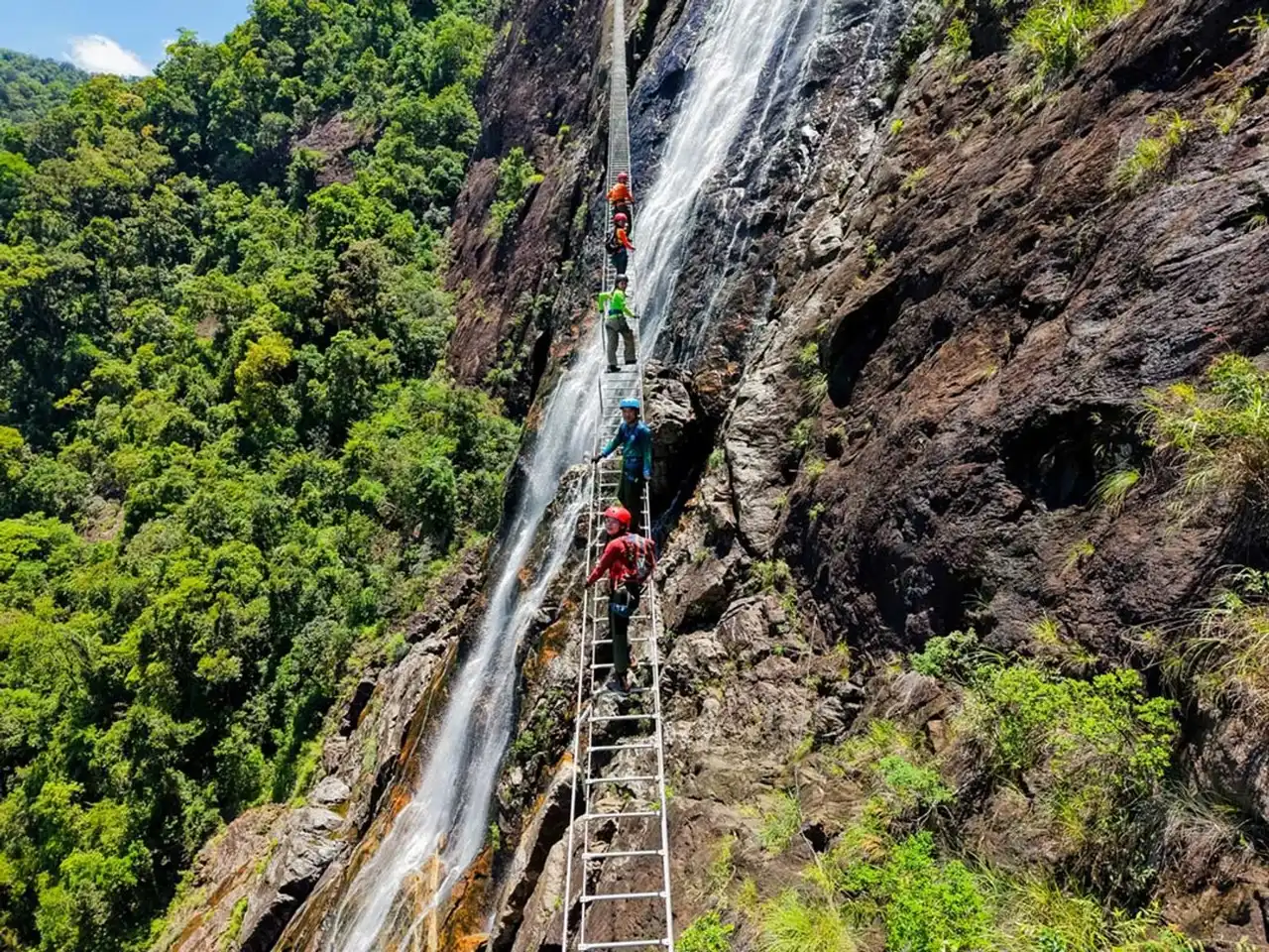 A climber on the via ferrata ladder beside the Do Quyen waterfall