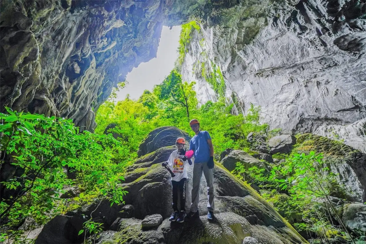 Two trekkers on boulders at the entrance to Elephant Cave
