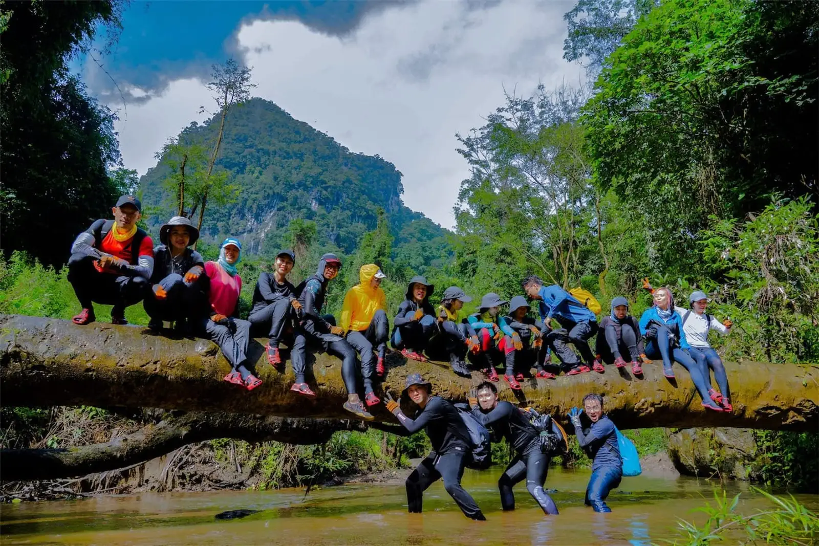 A group sitting along a fallen trunk over a river in Ma Da Valley