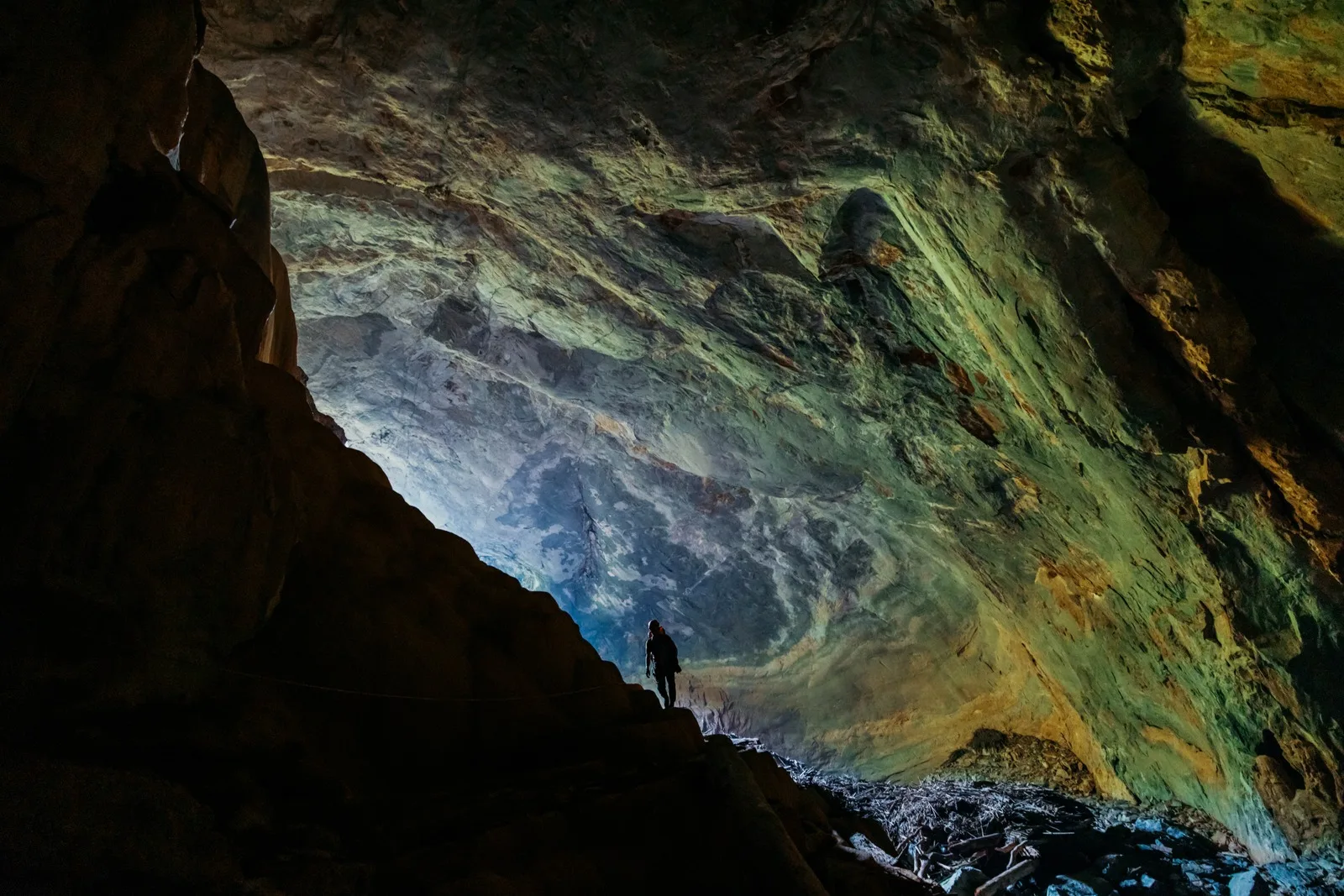 A lone caver lighting the far wall of the main chamber in Hang Pygmy