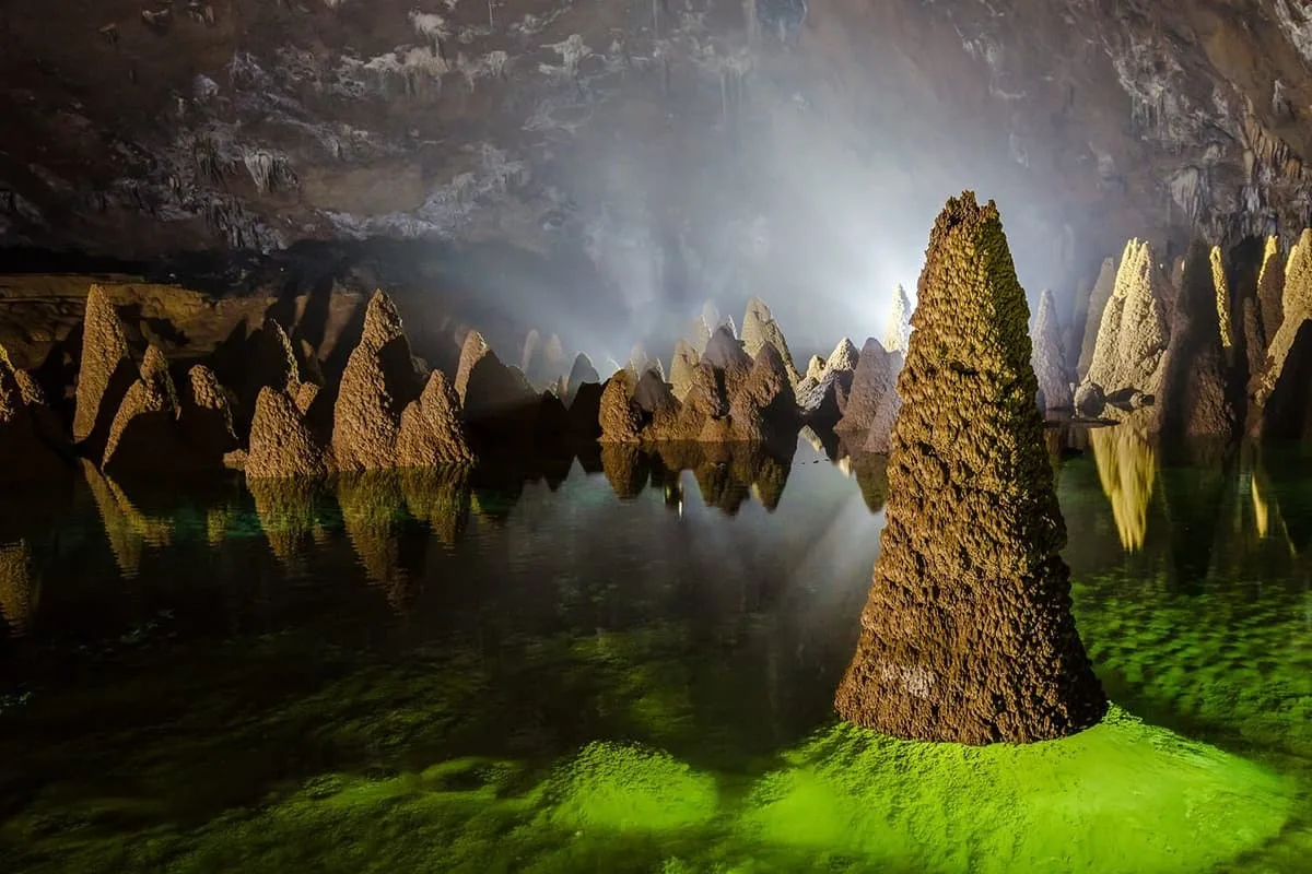 The cone stalagmites rising from the flooded gallery in Hang Va