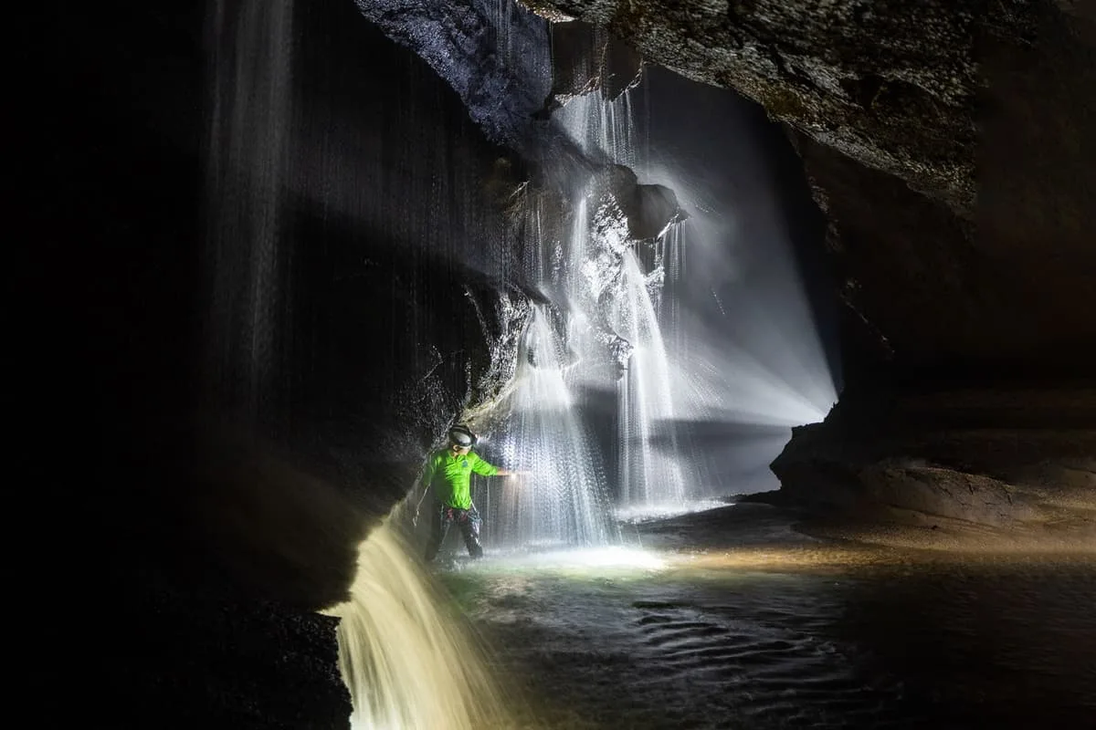 A waterfall inside Hang Va lit from below by a caver's lamp