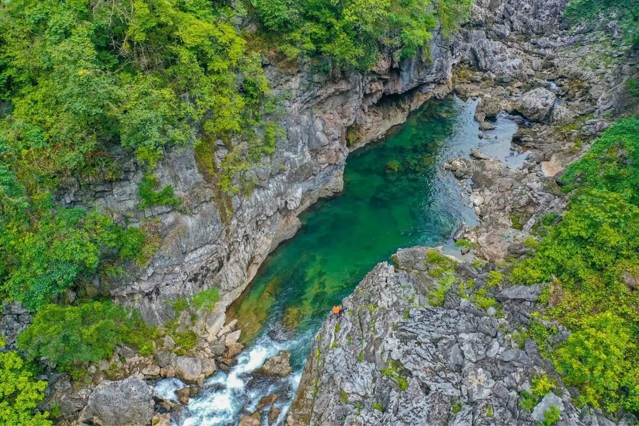 A turquoise river running through a limestone gorge above Hung Thoong