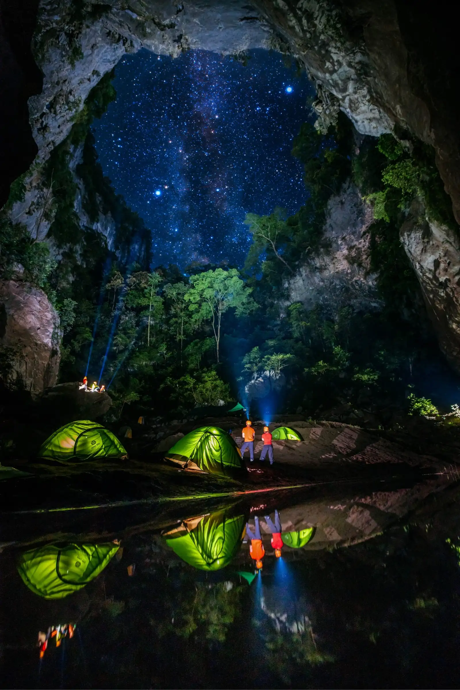 Lit tents reflected in still water under a starry sky on the Kong Collapse expedition