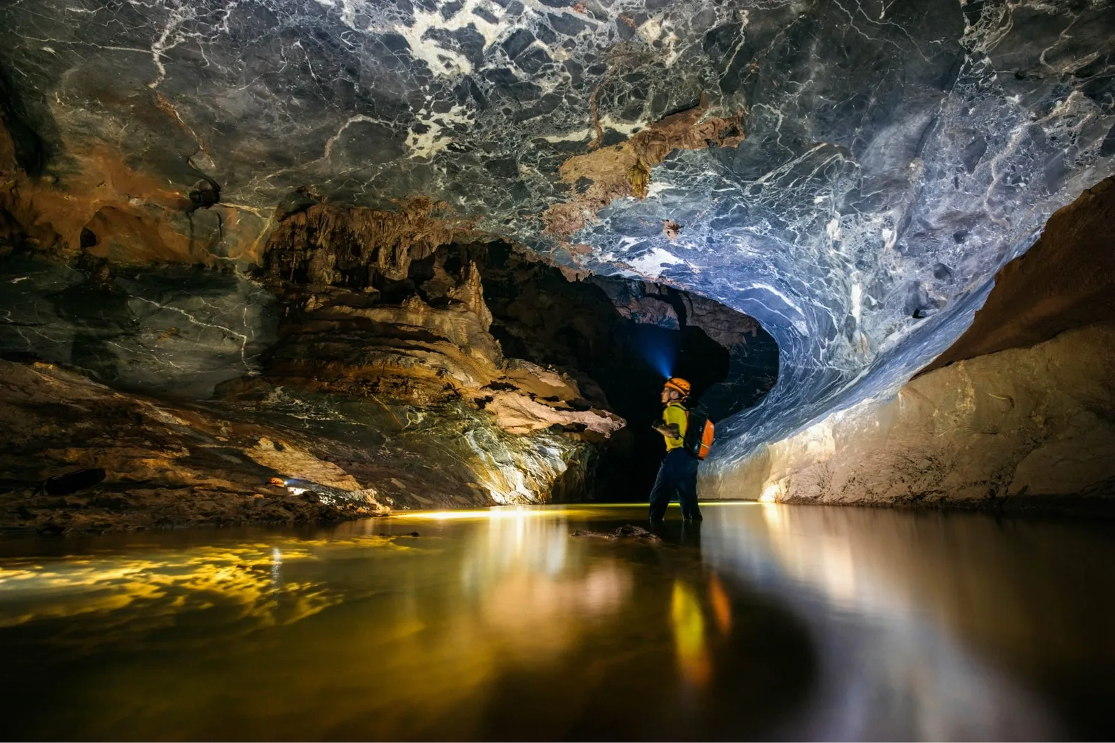 An underground river reflecting lamplight inside the Kong Collapse system