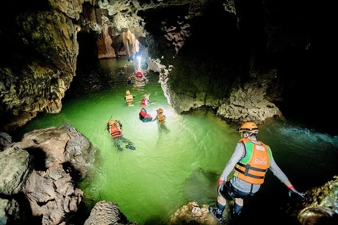 Swimmers in life jackets in the lit pool inside Hang Nuoc Nut