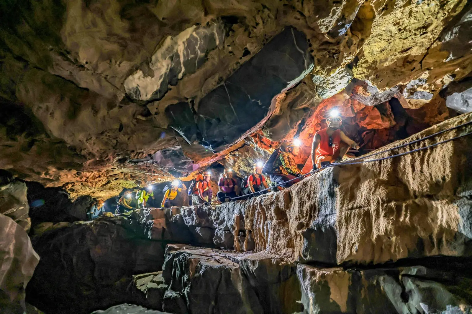 A line of cavers with headlamps traversing a gallery in Tiger Cave